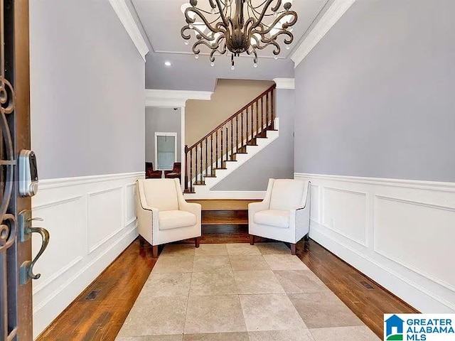 sitting room featuring a notable chandelier, stairway, wood finished floors, and ornamental molding