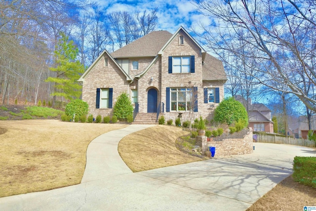 view of front of property with brick siding, fence, and roof with shingles