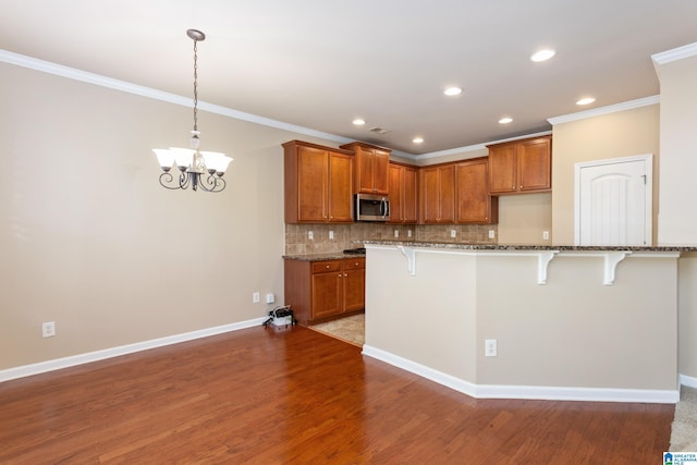 kitchen with crown molding, decorative backsplash, stone counters, and a kitchen bar