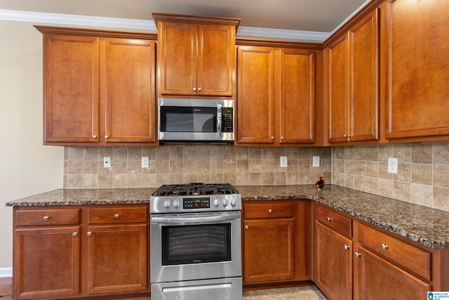 kitchen featuring backsplash, ornamental molding, stainless steel appliances, and dark stone countertops