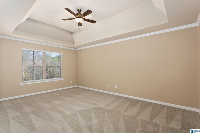 empty room featuring light carpet, ornamental molding, a raised ceiling, and ceiling fan