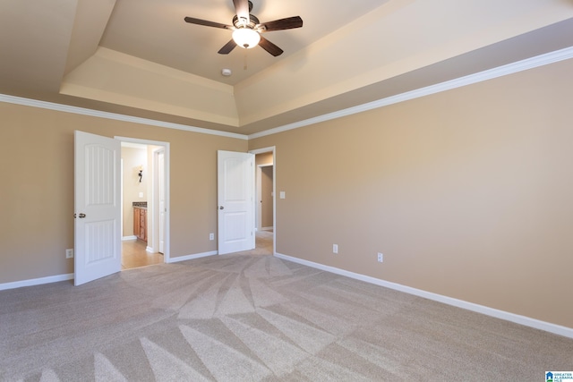 unfurnished bedroom featuring crown molding, light colored carpet, a tray ceiling, and ensuite bath