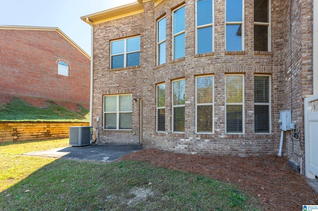 rear view of property with cooling unit, a lawn, and a patio