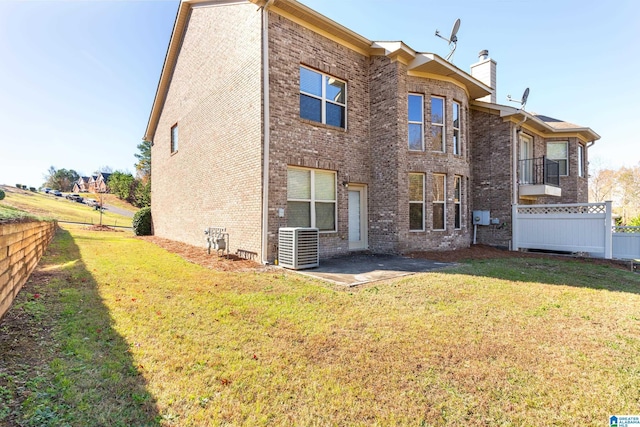 back of property with a patio, a yard, and central AC