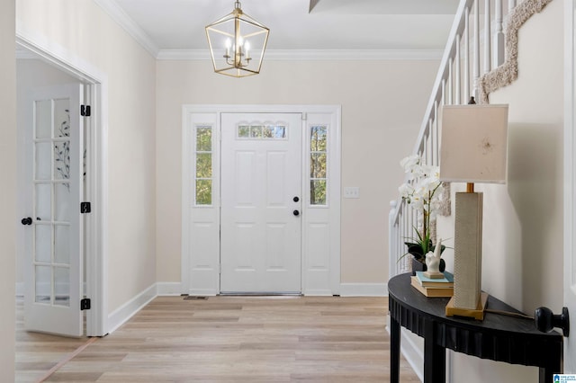 entryway with ornamental molding, a notable chandelier, and light hardwood / wood-style floors