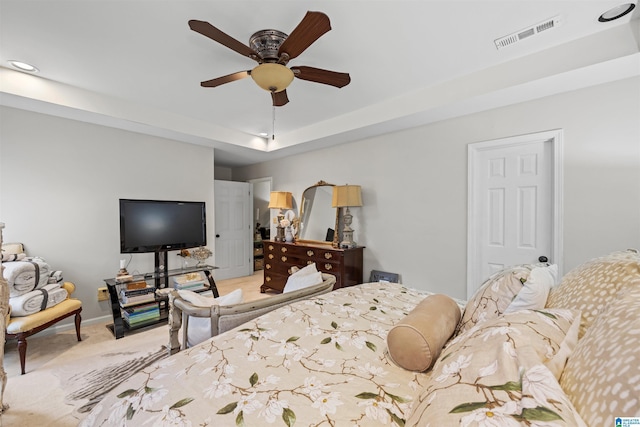 carpeted bedroom with ceiling fan and a tray ceiling