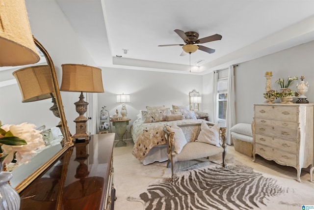 bedroom with a raised ceiling, light carpet, and ceiling fan