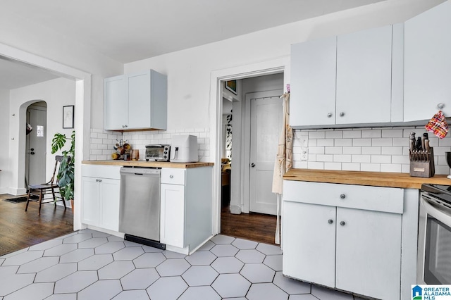 kitchen featuring tasteful backsplash, arched walkways, white cabinets, appliances with stainless steel finishes, and wooden counters