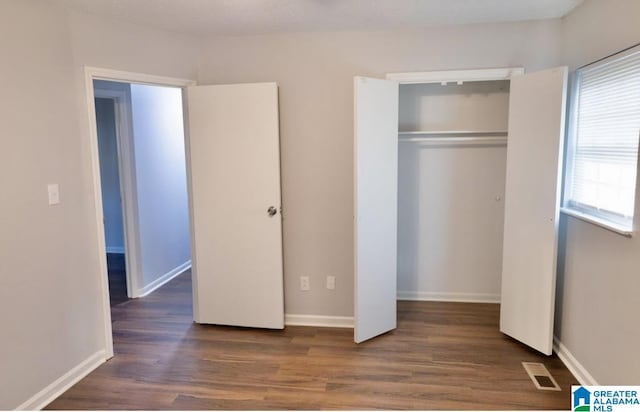 unfurnished bedroom with dark wood-type flooring and a closet