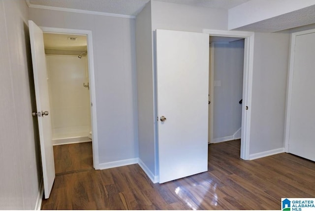 unfurnished bedroom featuring dark wood-type flooring, a closet, crown molding, and a textured ceiling