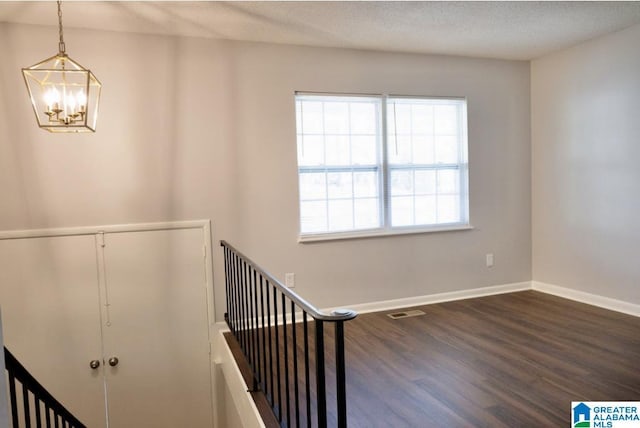 stairway with hardwood / wood-style floors, a chandelier, and a textured ceiling