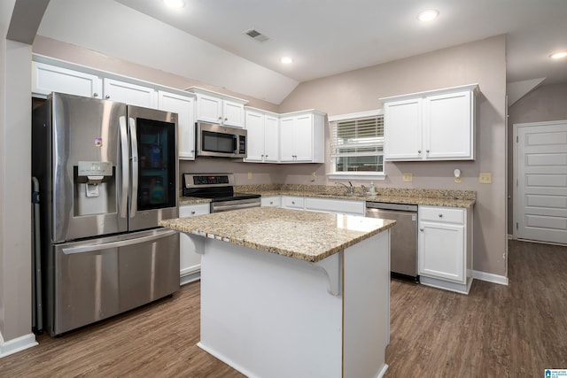 kitchen with a kitchen island, appliances with stainless steel finishes, white cabinets, and light stone counters
