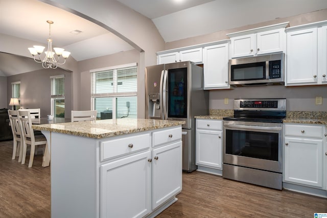 kitchen featuring appliances with stainless steel finishes, white cabinetry, a center island, decorative light fixtures, and vaulted ceiling