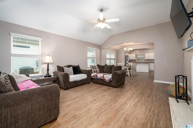 living room featuring lofted ceiling, ceiling fan with notable chandelier, and light wood-type flooring