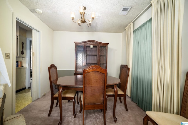 carpeted dining room featuring a textured ceiling and a chandelier