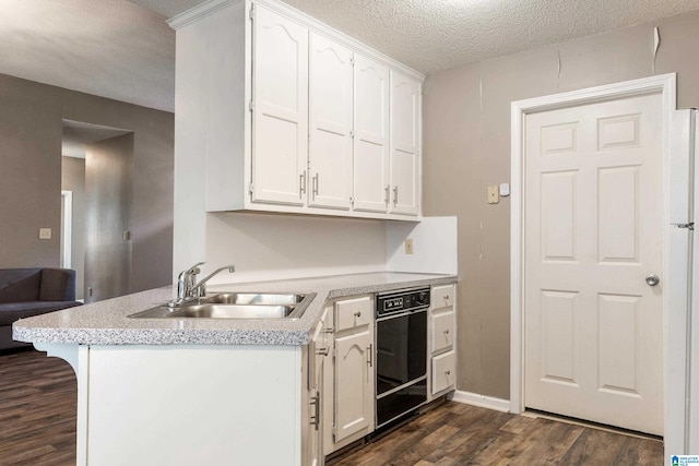 kitchen featuring white cabinetry, sink, kitchen peninsula, dark wood-type flooring, and a textured ceiling