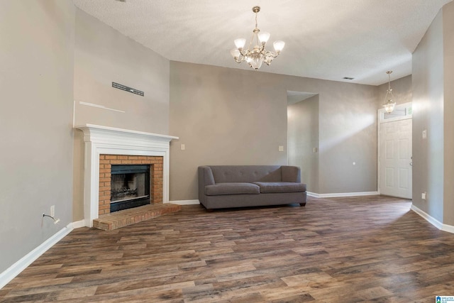 unfurnished living room featuring dark hardwood / wood-style floors, an inviting chandelier, a textured ceiling, and a fireplace