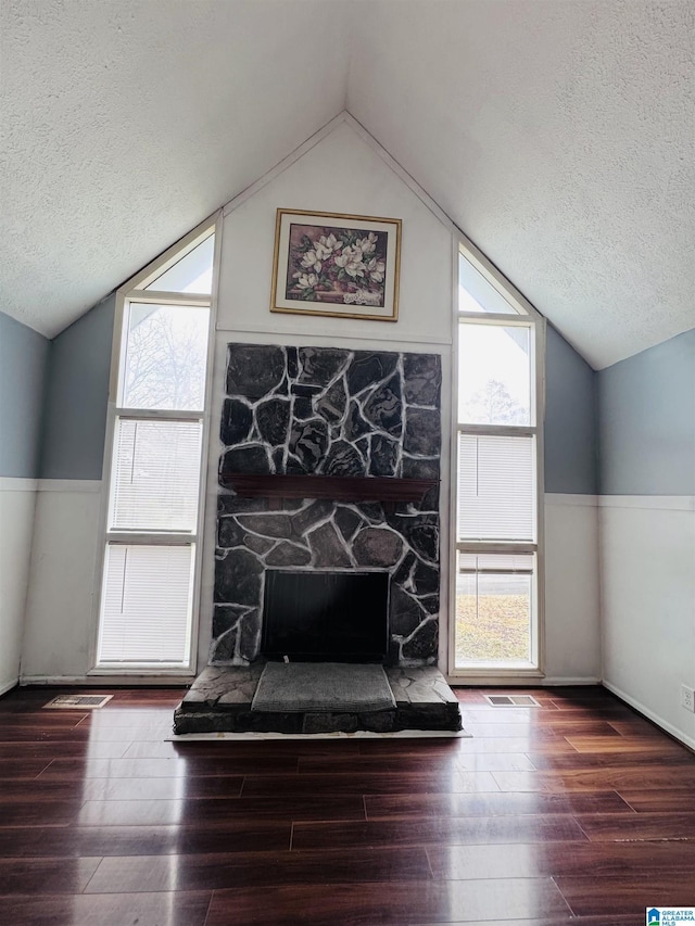 details with hardwood / wood-style floors, a stone fireplace, and a textured ceiling