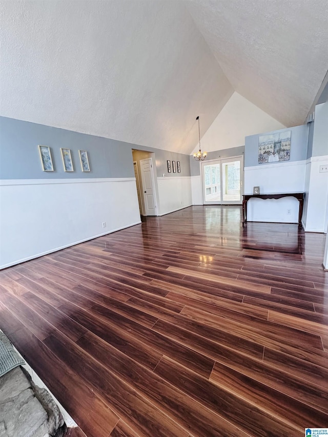 unfurnished living room with a textured ceiling, vaulted ceiling, dark hardwood / wood-style floors, and a chandelier