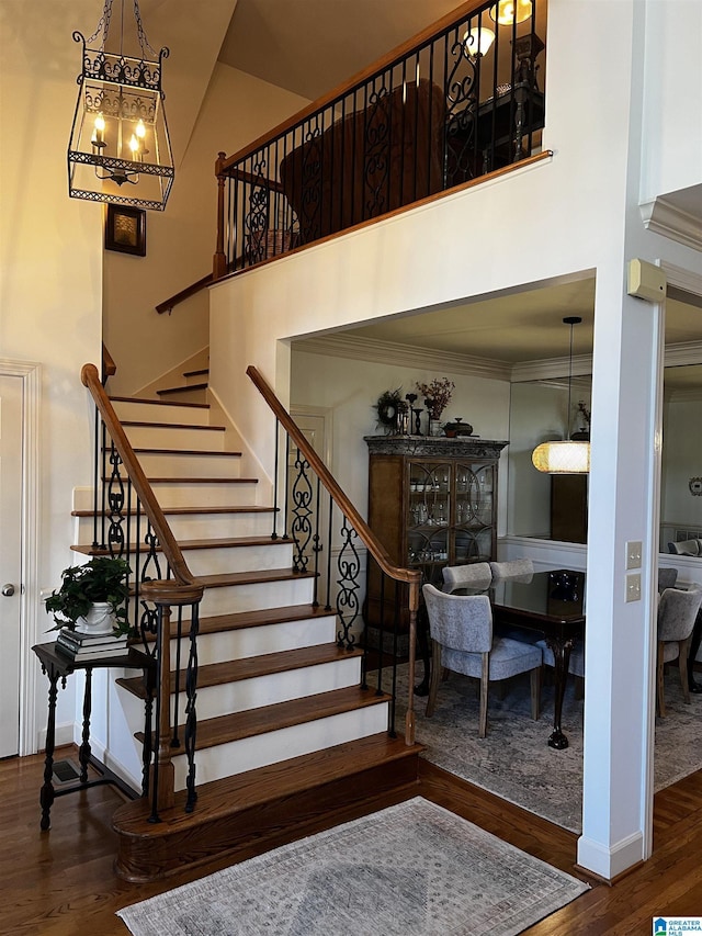 stairway with a towering ceiling, baseboards, and wood finished floors