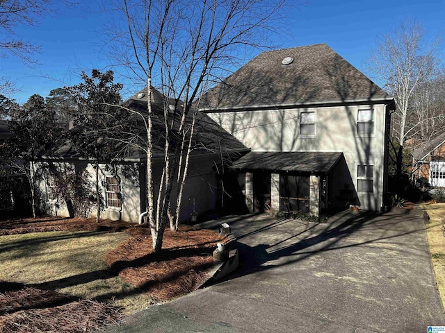 view of front facade featuring a shingled roof and driveway