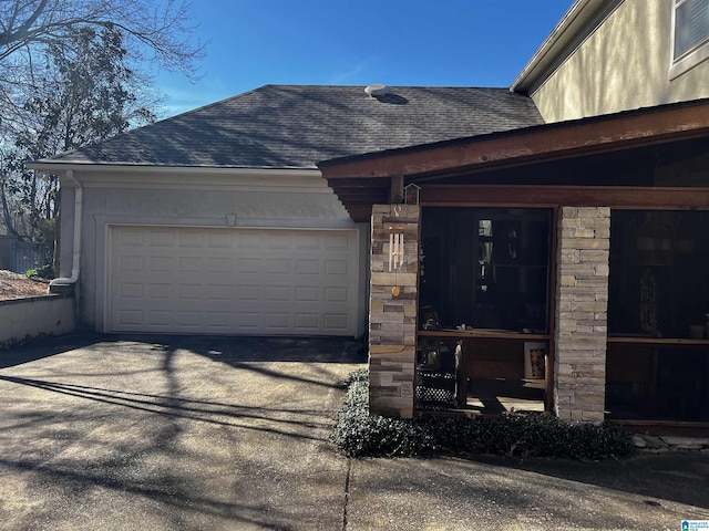 view of property exterior with a garage, stone siding, a shingled roof, and driveway