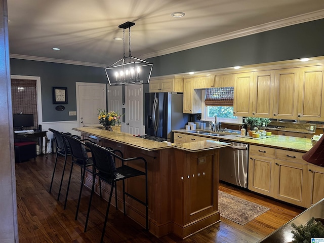 kitchen with a center island, dark wood finished floors, stainless steel appliances, hanging light fixtures, and a sink