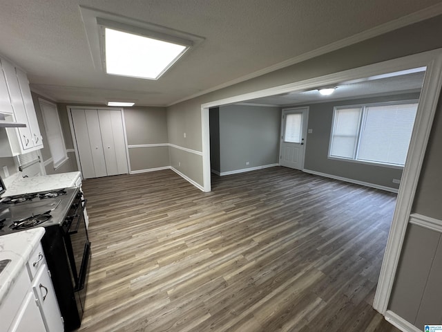 kitchen featuring black range, light stone counters, wood finished floors, and white cabinets