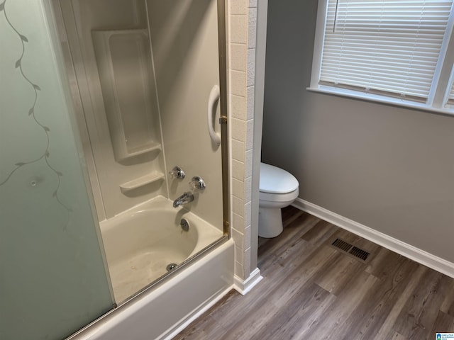 full bathroom with bath / shower combo with glass door, visible vents, toilet, wood finished floors, and baseboards