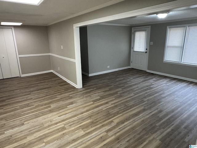 spare room featuring baseboards, dark wood-style flooring, and crown molding