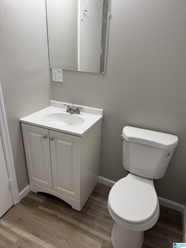 bathroom featuring toilet, wood finished floors, vanity, and baseboards