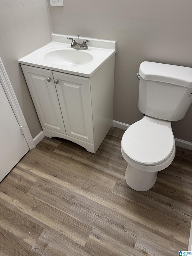 bathroom with baseboards, vanity, toilet, and wood finished floors