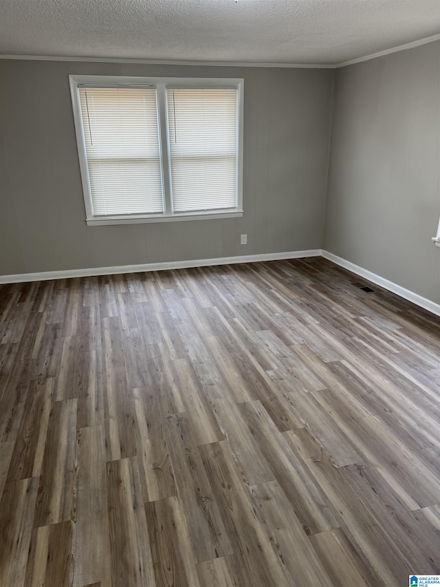 unfurnished room with a textured ceiling, crown molding, and wood finished floors