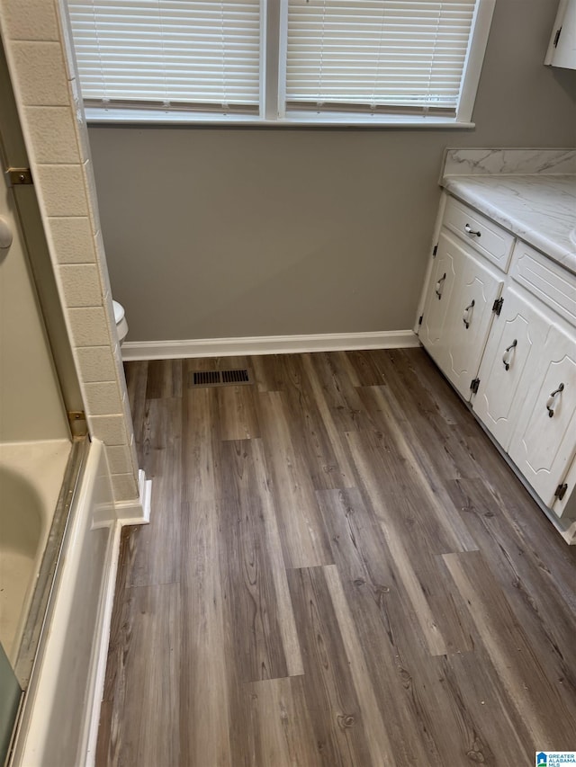 bathroom featuring baseboards, visible vents, toilet, wood finished floors, and vanity