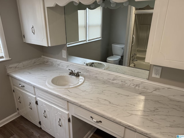 full bath with toilet, vanity, wood finished floors,  shower combination, and baseboards