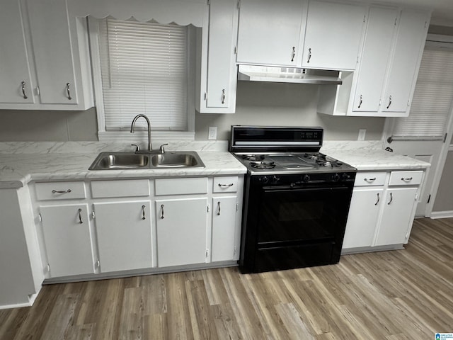 kitchen with under cabinet range hood, light countertops, a sink, and gas stove