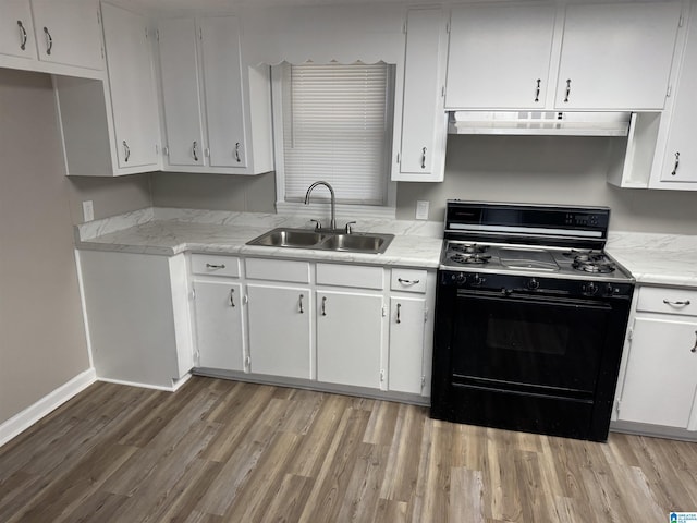 kitchen featuring gas stove, light countertops, a sink, and under cabinet range hood