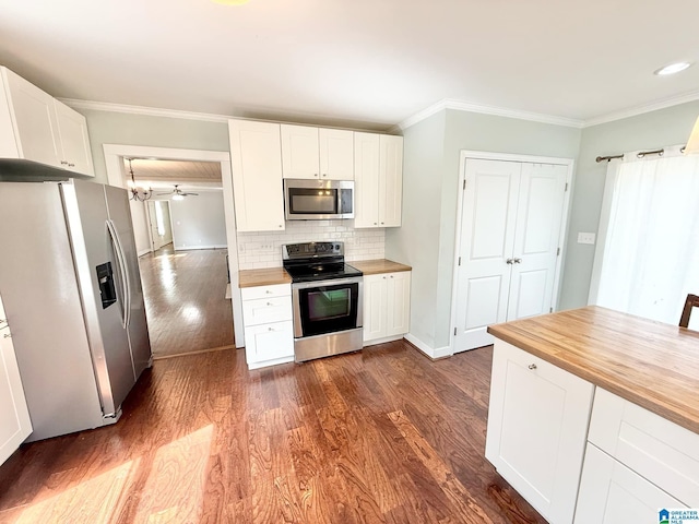 kitchen featuring butcher block counters, appliances with stainless steel finishes, dark wood-type flooring, and ornamental molding