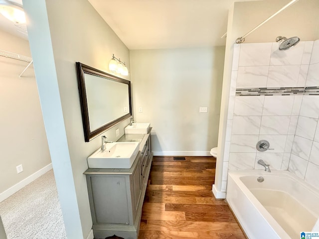 full bathroom featuring  shower combination, wood finished floors, a sink, and baseboards