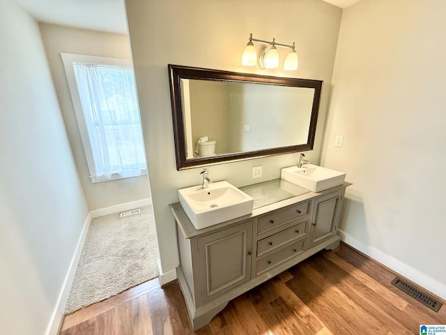 bathroom featuring baseboards, visible vents, a sink, and wood finished floors