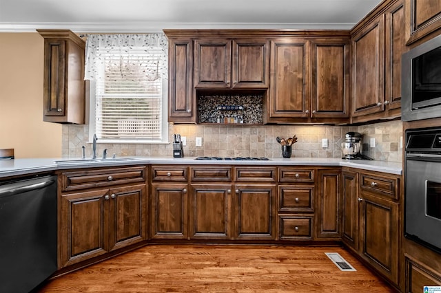 kitchen with a sink, stainless steel appliances, light countertops, and light wood-style floors