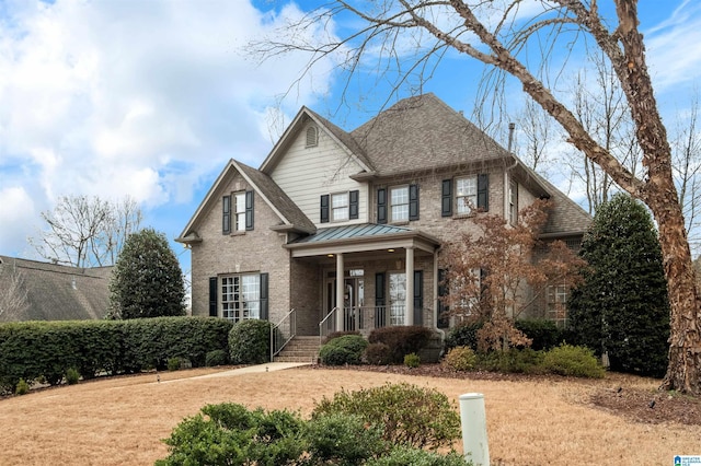 view of front of house featuring brick siding, a front lawn, and roof with shingles