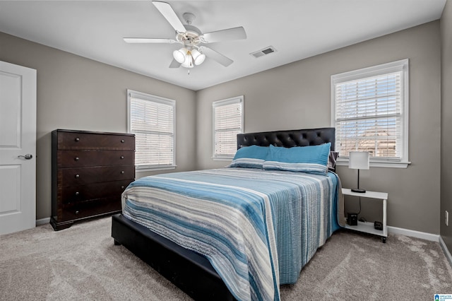 bedroom with light carpet, a ceiling fan, visible vents, and baseboards