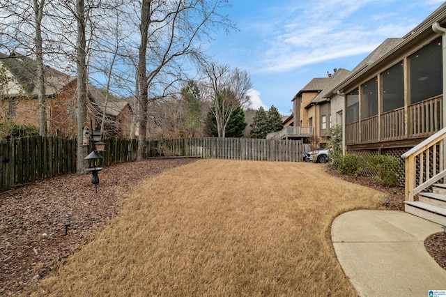 view of yard featuring a sunroom and a fenced backyard