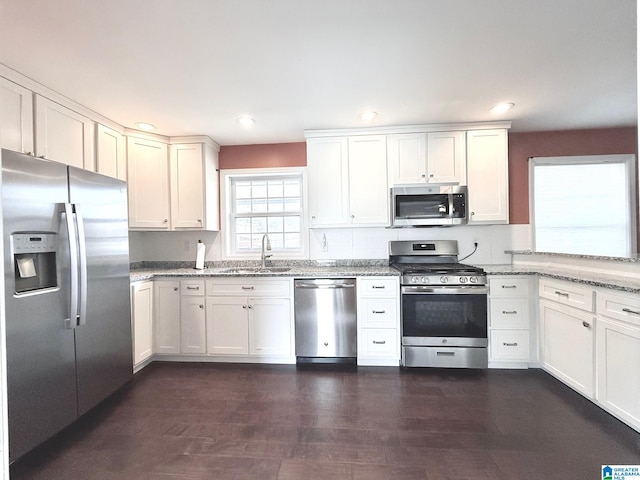 kitchen with light stone countertops, appliances with stainless steel finishes, sink, and white cabinets