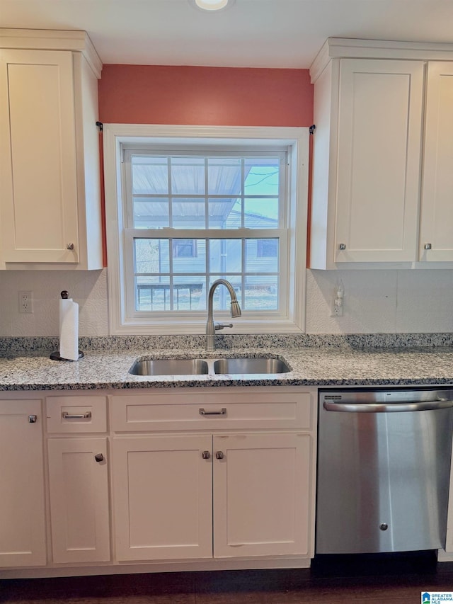 kitchen featuring white cabinetry, sink, stainless steel dishwasher, and light stone countertops