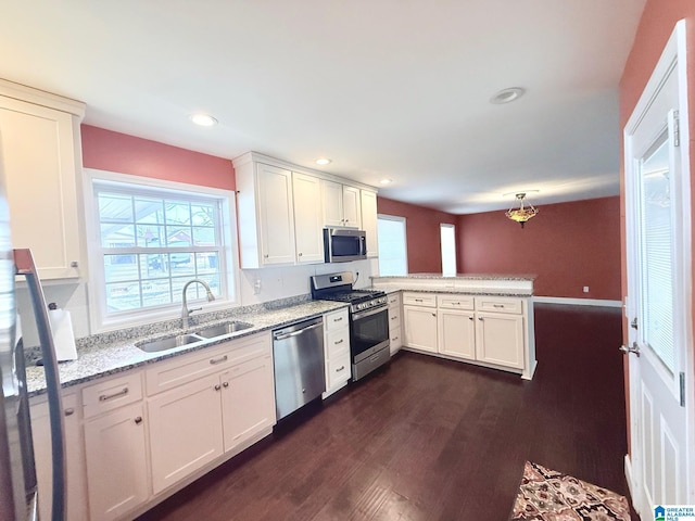 kitchen featuring sink, kitchen peninsula, white cabinets, and appliances with stainless steel finishes