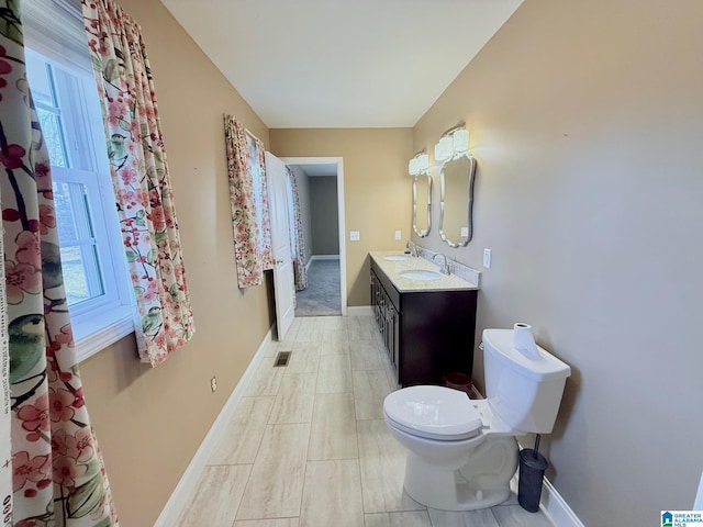 bathroom featuring vanity, plenty of natural light, and toilet