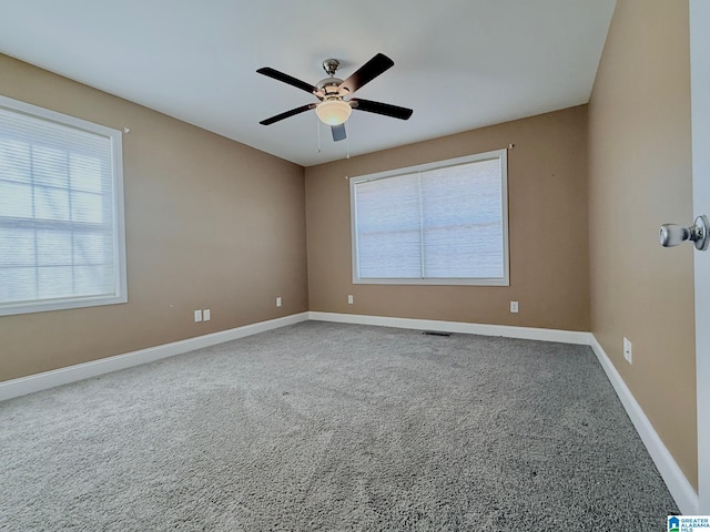 carpeted spare room featuring plenty of natural light and ceiling fan