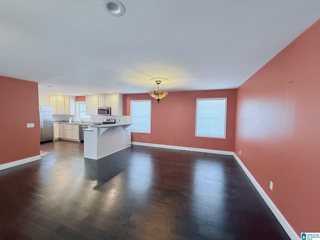 kitchen with a kitchen island, pendant lighting, a breakfast bar area, white cabinets, and stainless steel appliances